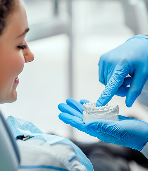 dentist using a model of teeth to explain something to a patient