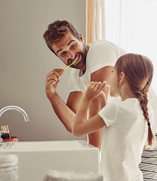 father and daughter brushing their teeth together