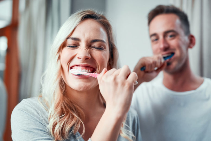 Couple brushing their teeth together to maintain good oral hygiene
